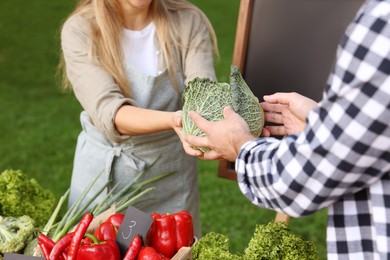 Photo of Man choosing fresh vegetables from stall at farmer's market, closeup