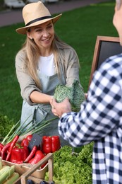 Photo of Man choosing fresh vegetables from stall at farmer's market, closeup