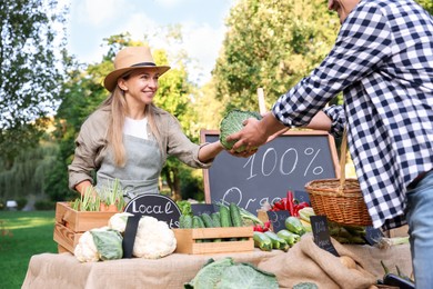 Photo of Man choosing fresh vegetables from stall at farmer's market, closeup