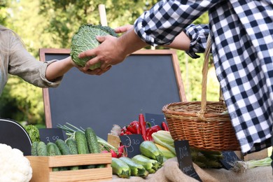 Photo of Man choosing fresh vegetables from stall at farmer's market, closeup
