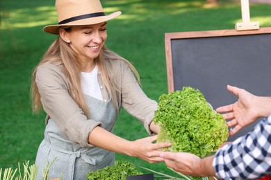 Photo of Man choosing fresh vegetables from stall at farmer's market, closeup