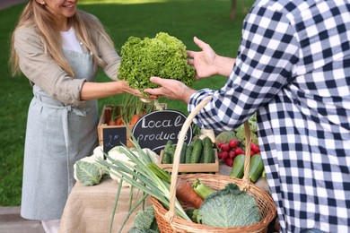 Photo of Man choosing fresh vegetables from stall at farmer's market, closeup