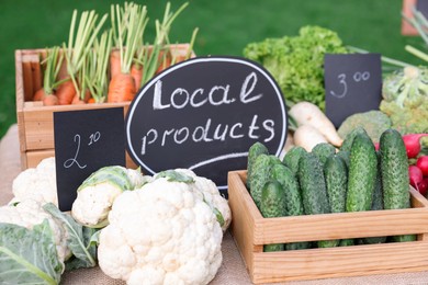 Photo of Many different vegetables and Local Products sign on stall at farmer's market, closeup