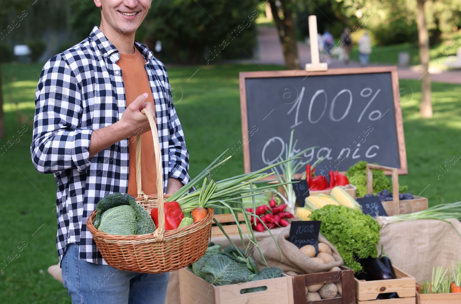 Photo of Man with different vegetables in wicker basket at farmer's market, closeup