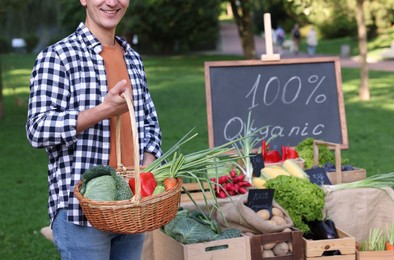 Photo of Man with different vegetables in wicker basket at farmer's market, closeup