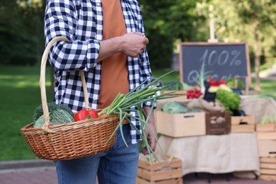 Photo of Man with different vegetables in wicker basket at farmer's market, closeup