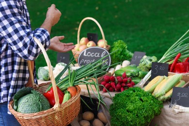 Photo of Man choosing fresh vegetables from stall at farmer's market, closeup