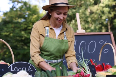 Photo of Happy farmer near stall with different fresh vegetables at market