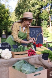Photo of Happy farmer near stall with different fresh vegetables at market