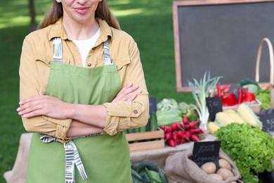 Photo of Farmer near stall with different fresh vegetables at market, closeup