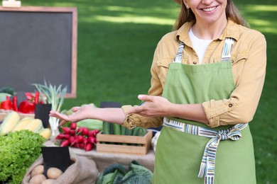 Photo of Farmer near stall with different fresh vegetables at market, closeup