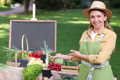 Photo of Happy farmer near stall with different fresh vegetables at market