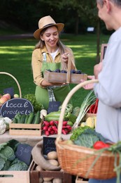 Photo of Man choosing fresh vegetables and plums from stall at farmer's market