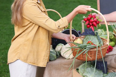 Photo of Woman choosing fresh vegetables from stall at farmer's market, closeup
