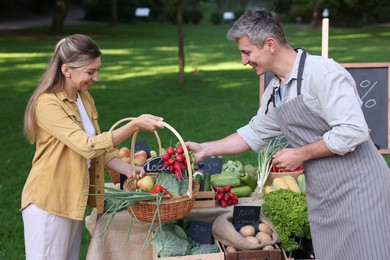 Photo of Woman choosing fresh vegetables from stall at farmer's market