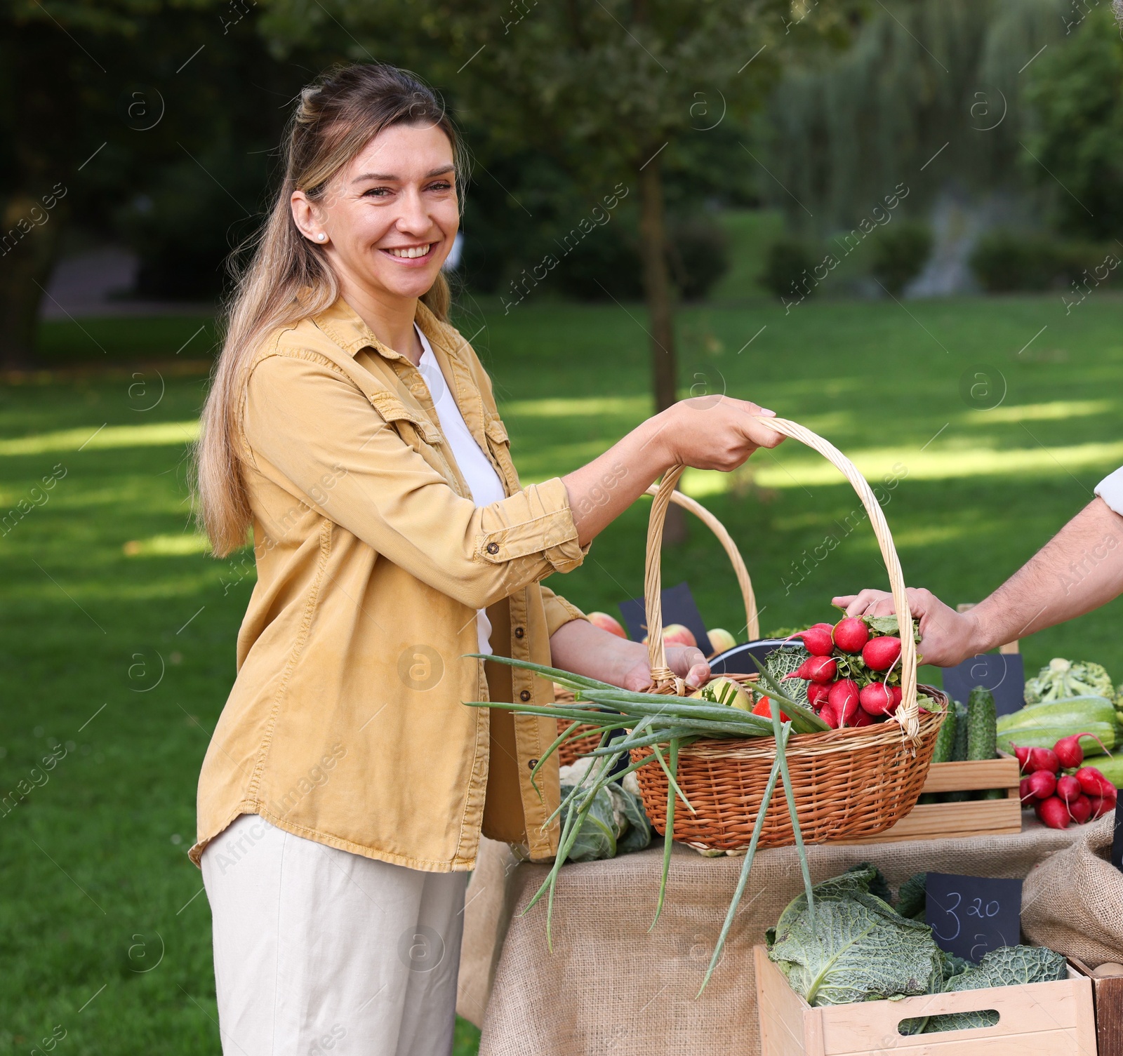 Photo of Woman choosing fresh vegetables from stall at farmer's market