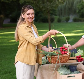 Photo of Woman choosing fresh vegetables from stall at farmer's market