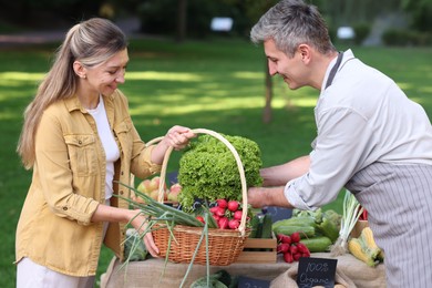 Photo of Woman choosing fresh vegetables from stall at farmer's market
