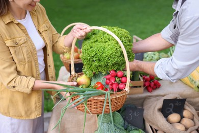 Photo of Woman choosing fresh vegetables from stall at farmer's market, closeup