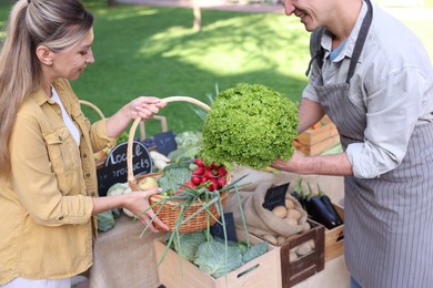 Photo of Woman choosing fresh vegetables from stall at farmer's market
