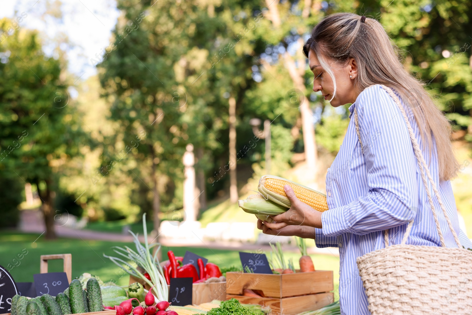 Photo of Woman choosing fresh vegetables from stall at farmer's market