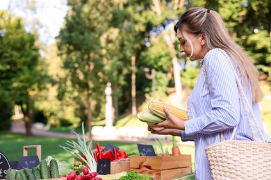 Photo of Woman choosing fresh vegetables from stall at farmer's market