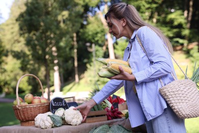 Photo of Woman choosing fresh vegetables from stall at farmer's market
