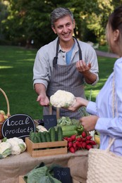 Photo of Woman choosing fresh vegetables from stall at farmer's market