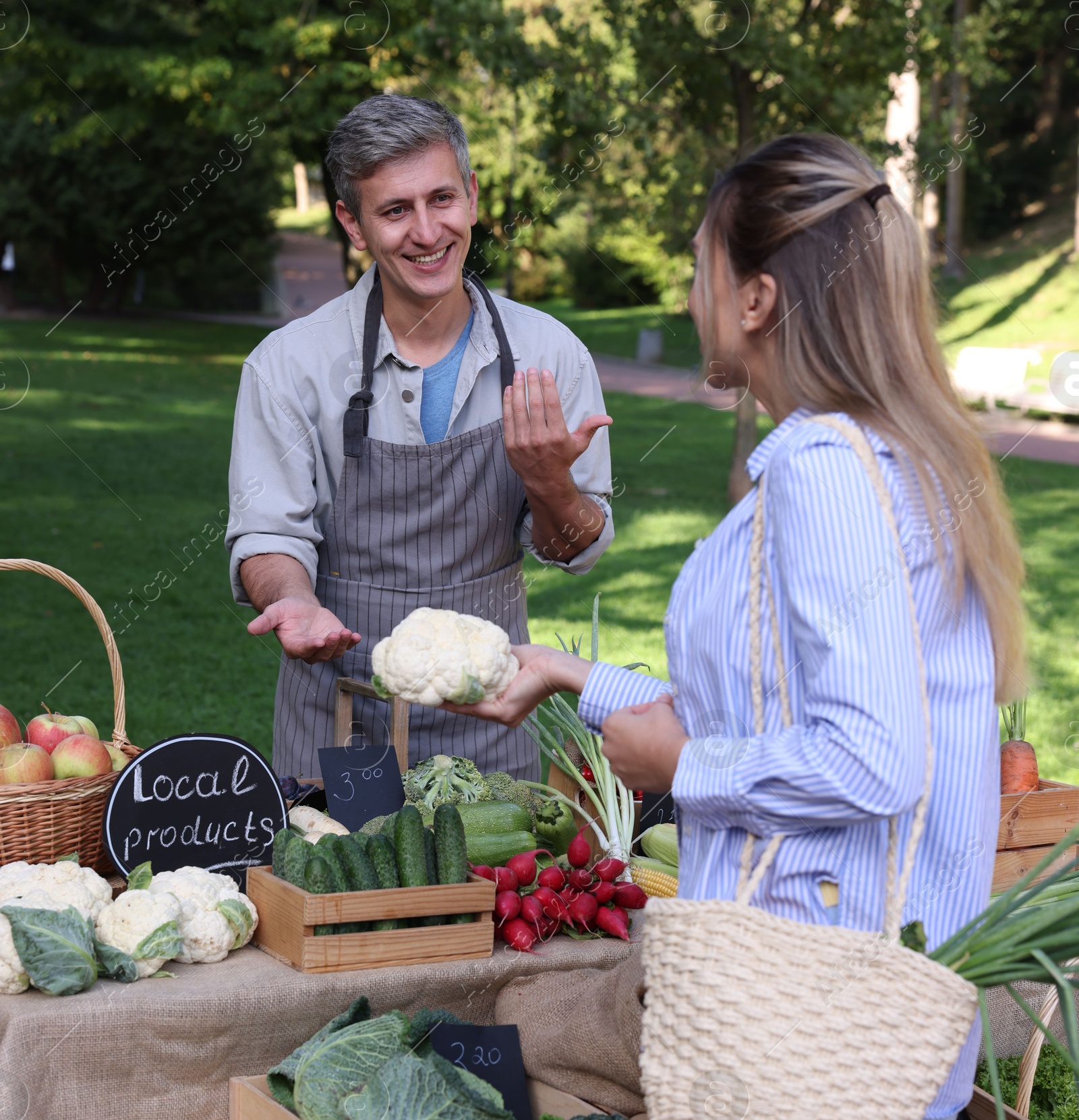 Photo of Woman choosing fresh vegetables from stall at farmer's market