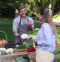 Photo of Woman choosing fresh vegetables from stall at farmer's market