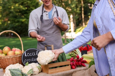 Photo of Woman choosing fresh vegetables from stall at farmer's market, closeup