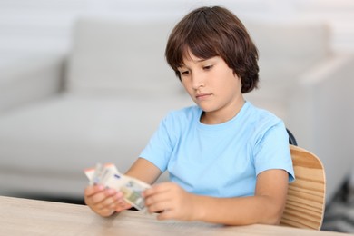 Photo of Boy with pocket money at wooden table indoors