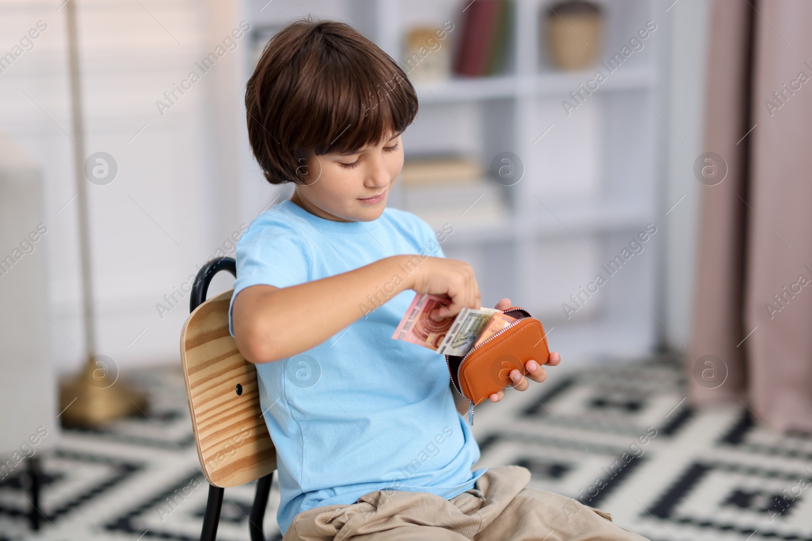 Photo of Boy putting his pocket money into wallet at home. Space for text