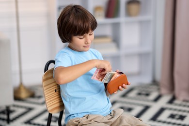 Photo of Boy putting his pocket money into wallet at home. Space for text