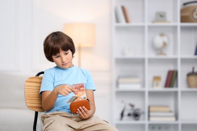 Photo of Boy putting his pocket money into wallet at home. Space for text