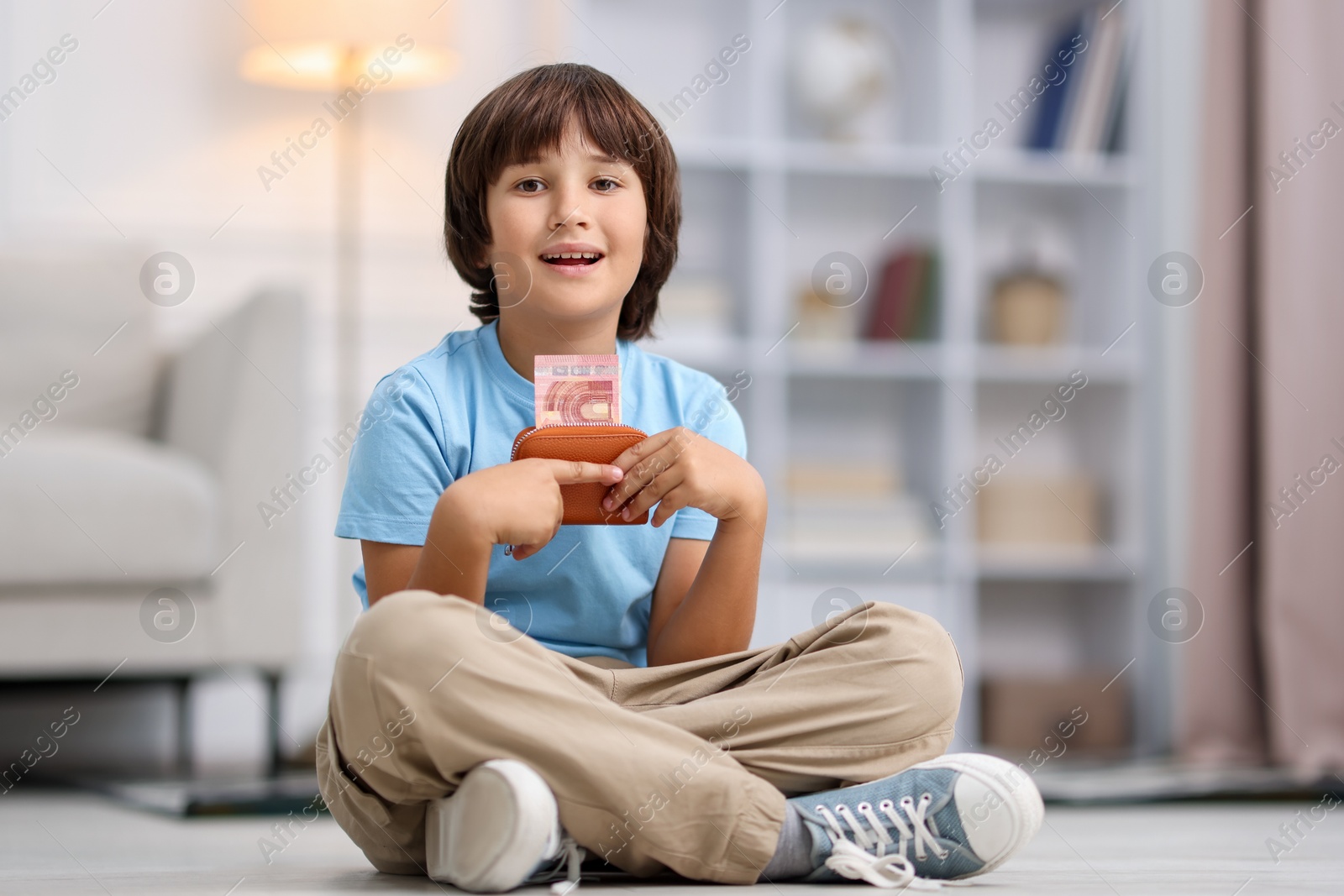 Photo of Boy with pocket money on floor at home
