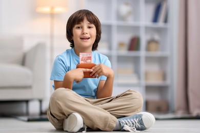 Photo of Boy with pocket money on floor at home