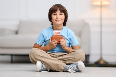 Photo of Boy with pocket money on floor at home
