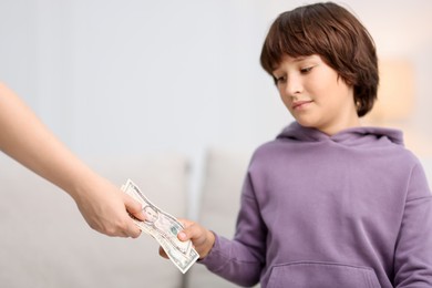 Photo of Mother giving her son pocket money at home, closeup. Space for text
