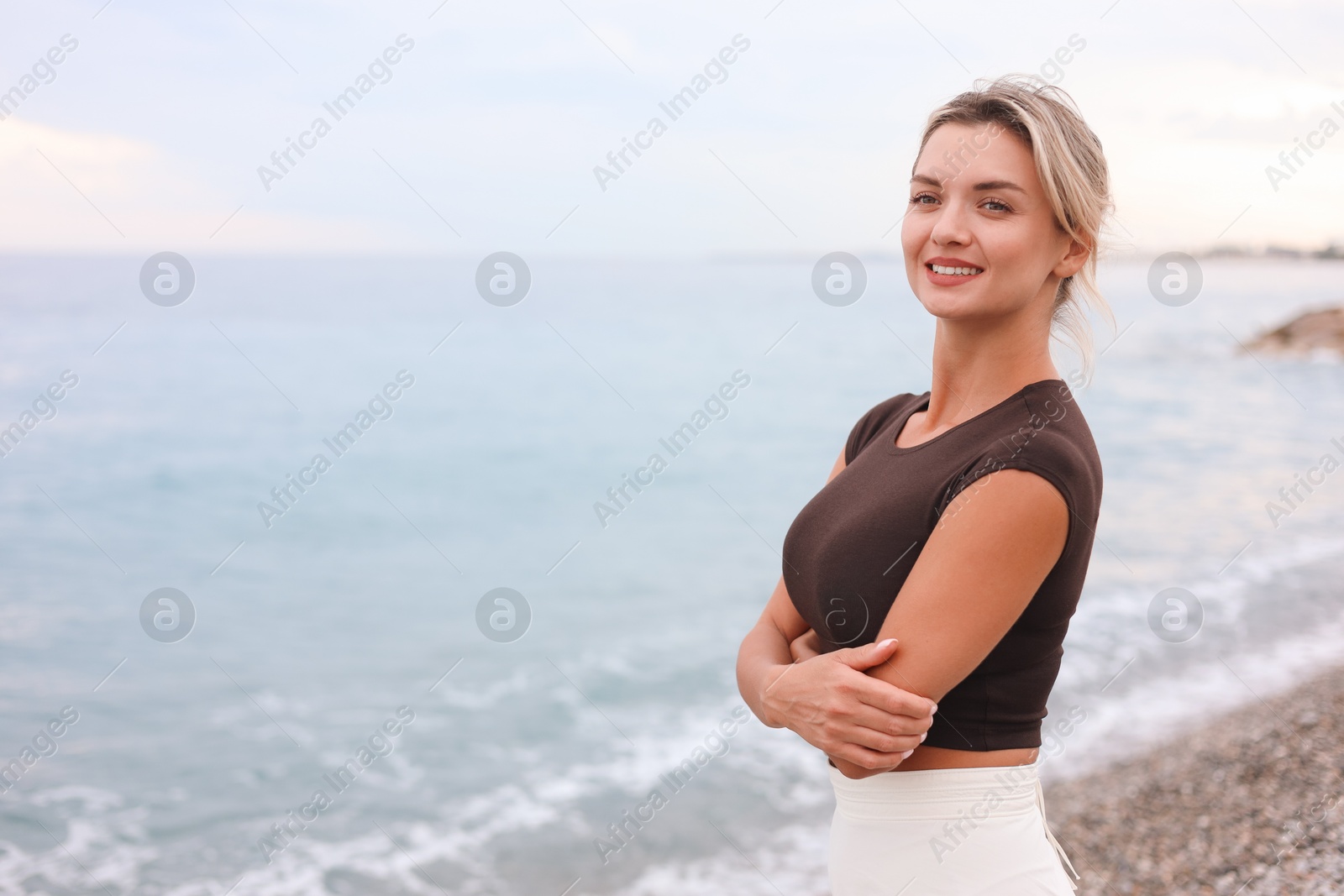 Photo of Beautiful young woman near sea on beach, space for text
