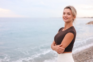 Photo of Beautiful young woman near sea on beach, space for text