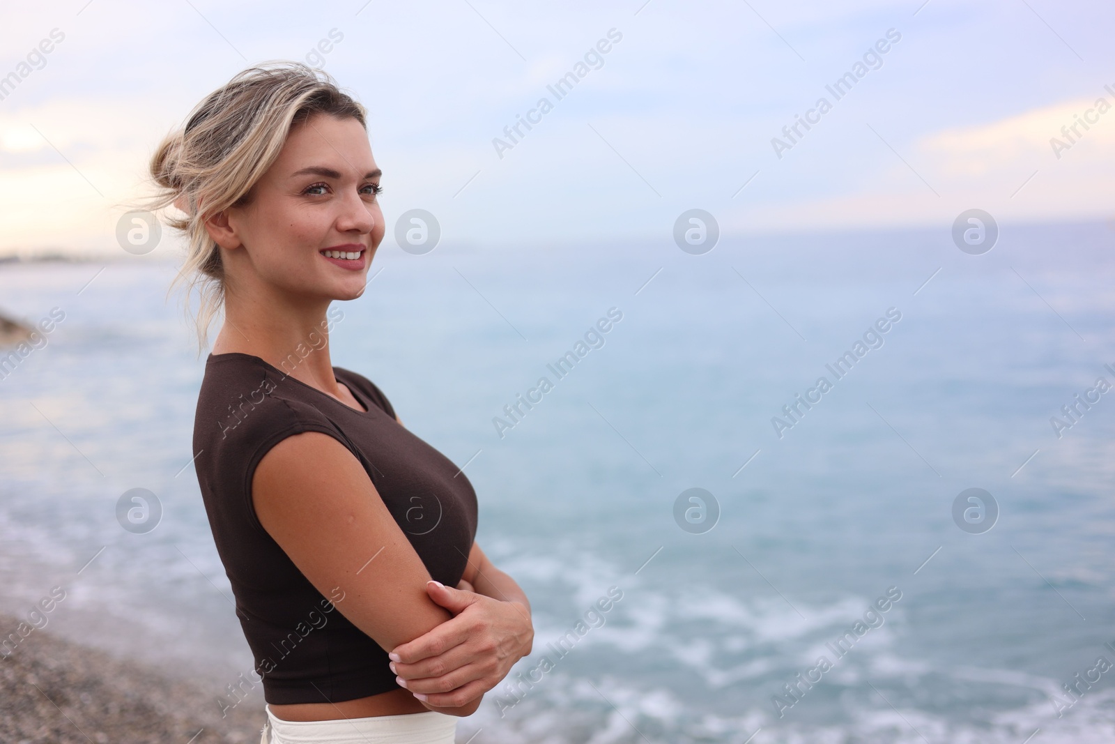 Photo of Beautiful young woman near sea on beach, space for text
