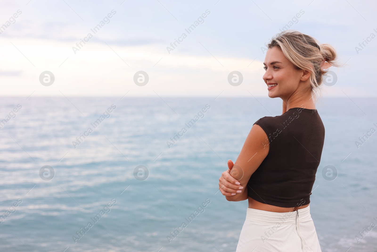 Photo of Beautiful young woman near sea on beach, space for text