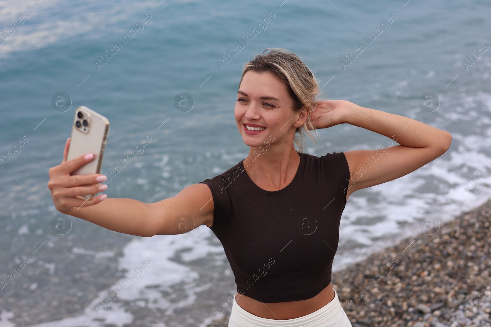 Photo of Beautiful young woman taking selfie on beach