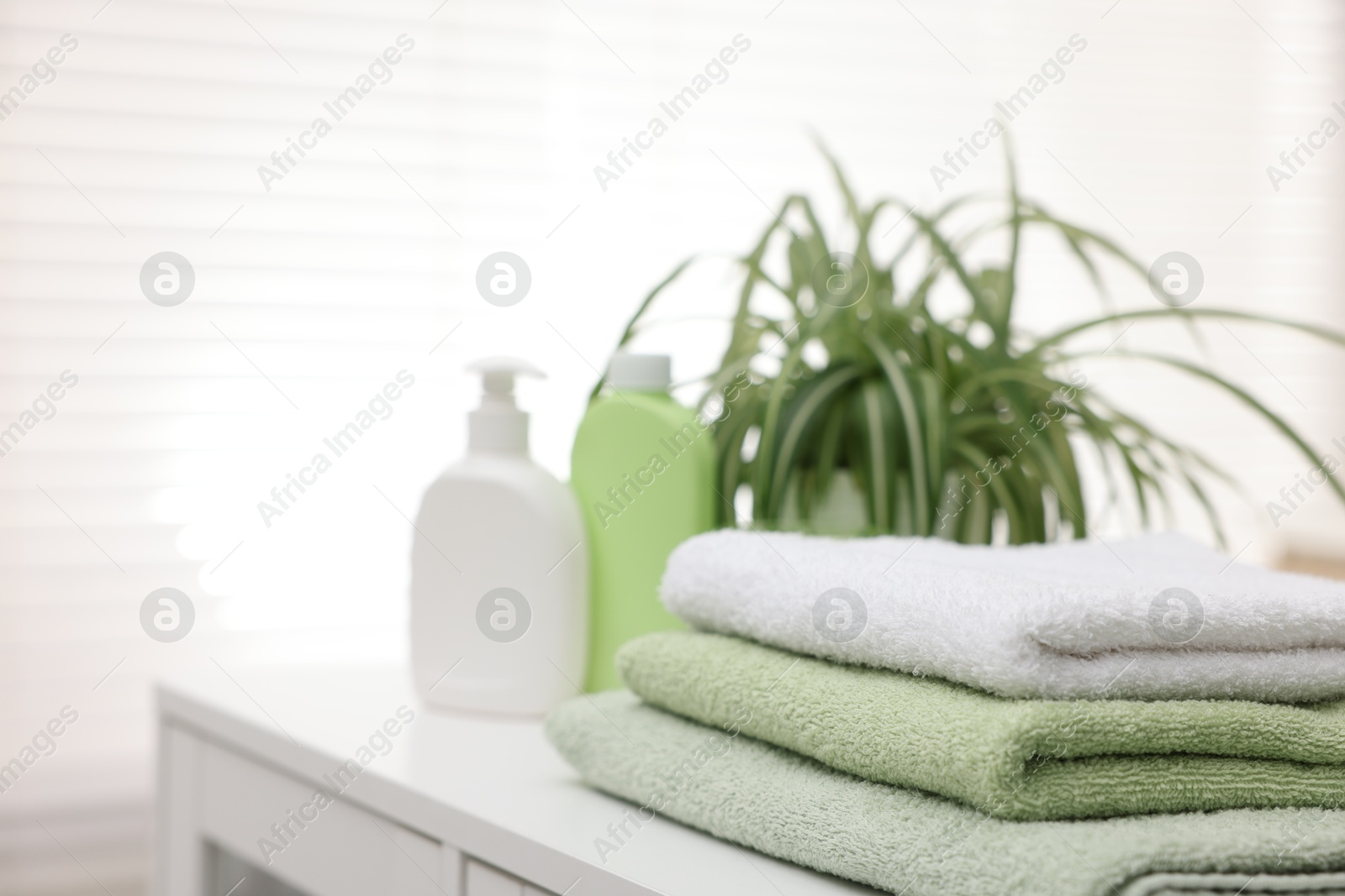 Photo of Stack of fresh terry towels on white table in bathroom, closeup. Space for text