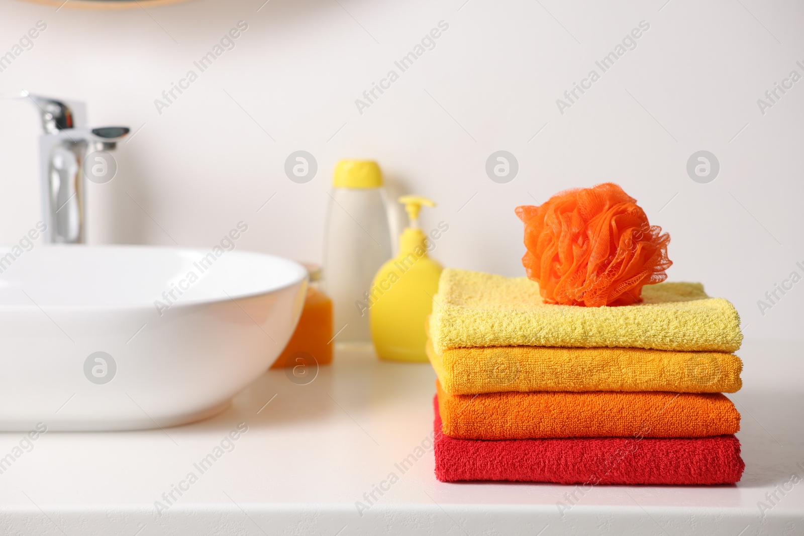 Stack of fresh terry towels and sponge on counter near sink Photo of Stack of fresh terry towels and sponge on counter near sink