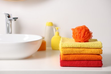 Photo of Stack of fresh terry towels and sponge on counter near sink
