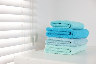 Photo of Stack of fresh terry towels on white table in bathroom. Space for text