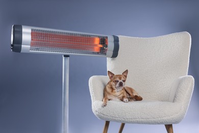 Photo of Cute little dog on armchair near electric heater against grey background