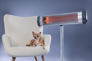 Photo of Cute little dog on armchair near electric heater against grey background